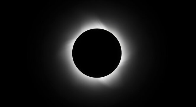 A total solar eclipse with the sun"s corona glowing brightly around the darkened moon.