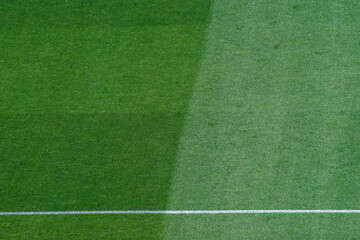 Obraz premium Background Texture of International-Standard Football Pitch with Striped Grass and Field Lines Under Clear Conditions