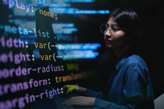 Young developer focused on coding in dimly lit room.  Tech and creativity merge in this quiet moment