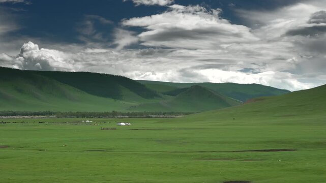 Panoramic view of treeless Mongolian steppe with ger tents across vast green plains. Wide landscape shows untouched meadow, distant hills, and traditional yurts in unspoiled countryside.