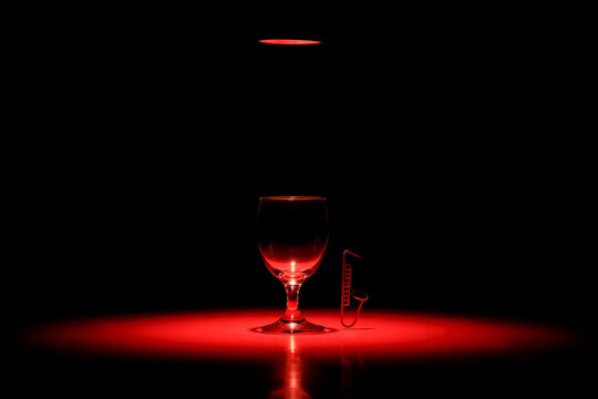 Jazz Bar Empty wine glass and saxophone charm illuminated by red light image