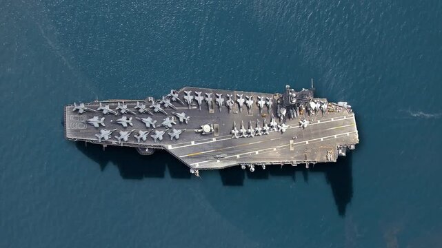 Aerial view of a modern aircraft carrier showcasing fighter jets ready for military operations in a strategic naval deployment