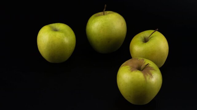 Four green apples in a motorized camera slider shot against a black background