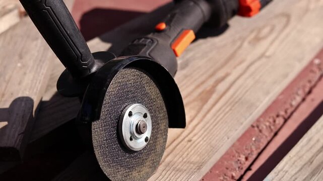 Professional black angle grinder with installed disc. Angle grinder with cutting disc on wooden surface. The tool lies in the workshop. Close-up, focus on the disc and metal mount