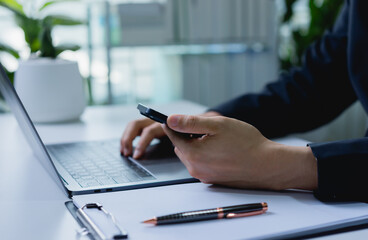 Fototapeta premium Businessman working with mobile phone and laptop, managing online marketing and investment, digital job workflow and business communication concept.