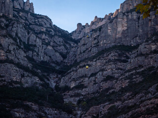 Fototapeta premium Montserrat monastery and cable car over rocky mountains at dusk in Catalonia