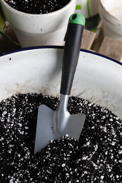 Gardening tool sitting in soil with potted plants in the background during daytime in a home garden
