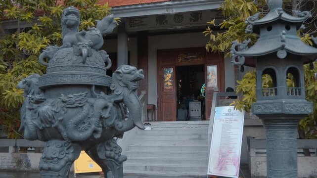 Traditional, large bronze incense burner heavily decorated with traditional carvings, including dragon figures around the main body and lion-like guardian creatures on the sides stands