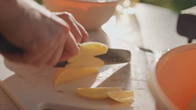 Camping prep details. Stabilized hands creating thin potato slices for camping meal prep. Precise knife skills used to carefully prepare potatoes for camping in compact outdoor setting