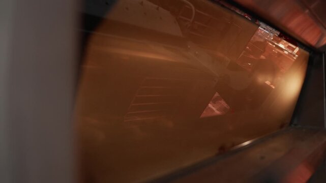 Freshly prepared dough rises inside a commercial oven, showcasing the gradual transformation of bread as it bakes under warm lighting in a professional kitchen setting