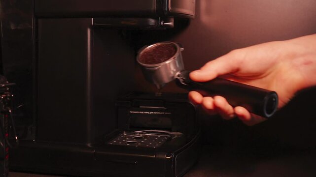 Close-up of a barista tempering freshly ground coffee with a tempera in a coffee shop. The process of making espresso. Footage of barista tamping coffee in pitcher of a barista crafting an Americano. 
