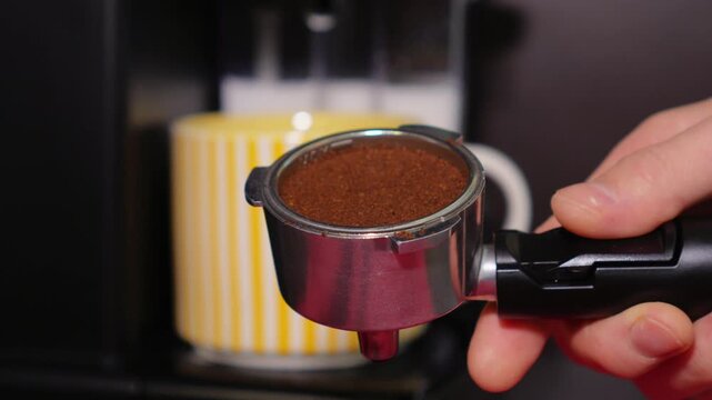 Close-up of a barista tempering freshly ground coffee with a tempera in a coffee shop. The process of making espresso. Footage of barista tamping coffee in pitcher of a barista crafting an Americano. 