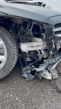 Vertical screen car crash accident broken bumper closeup damaged vehicle traffic violation consequences wrecked auto impact details urban road danger caution concept intense gritty scene