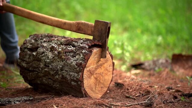 Man splitting a piece of log with an ax