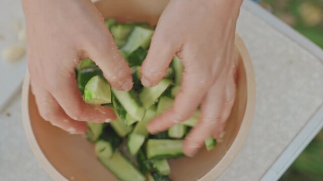 Fresh salad prep. Outdoor cucumber garlic mixture. Vibrant picnic style cucumber garlic salad. Casual campfire gathering featuring fresh cucumber and garlic salad with zesty marinade