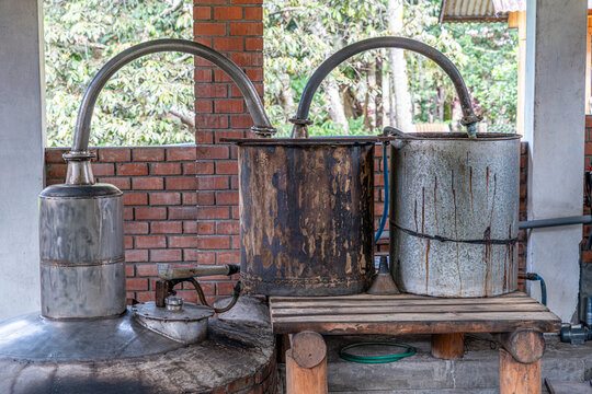 Rural sugarcane distillation equipment with copper stills and brick furnace, highlighting artisanal spirit production and cultural heritage.