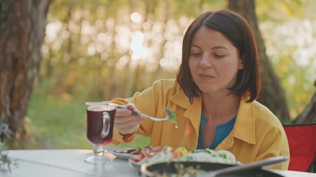Female lover relishing relaxing park meal. Enthusiastic woman delighting in leisurely outdoor dining experience. Woman embracing pleasure of peaceful park picnic with enthusiasm and joy