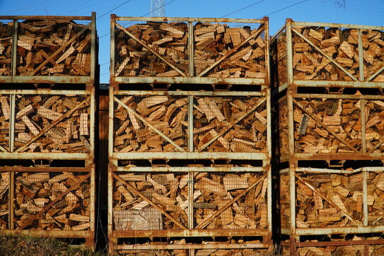 Dried firewood, stacked in metal boxes for sale. Natural energy for heating and cooking, Wunstorf Luthe, Germany