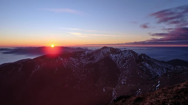 Mountain summit sunset timelapse with snow patches and valley inversion