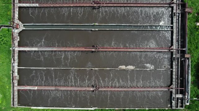 Aerial view of wastewater treatment aeration basins with bubbling influent at industrial plant lateral pan.
