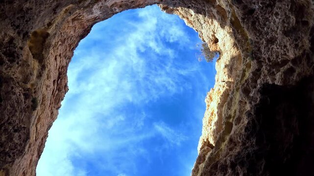 Looking Up Through Benagil Cave Opening to Blue Sky and Clouds in Algarve Portugal