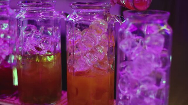 Barman mixing and pouring drinks and beverages, beautiful row line of different coloured lemonades in a jar, liquor alcohol cocktails on a party in bar, catering banquet on event, mocktails in a jug 