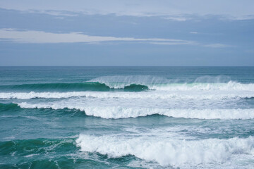 Fototapeta premium Breaking grand foamy waves of Atlantic Ocean in Portugal. Cloudy day, tide and seascape in the Guincho beach, Lisbon district.