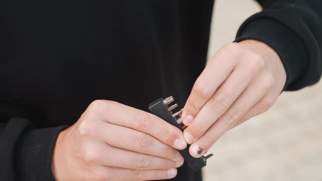 Closeup hands handling screwdriver bits white person outdoors, street technician inspecting metal set, focused fingertip placement, tactile grip and steady motion, daylight concrete background,