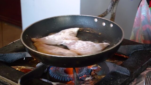 Chef frying fish in a pan in restaurant kitchen