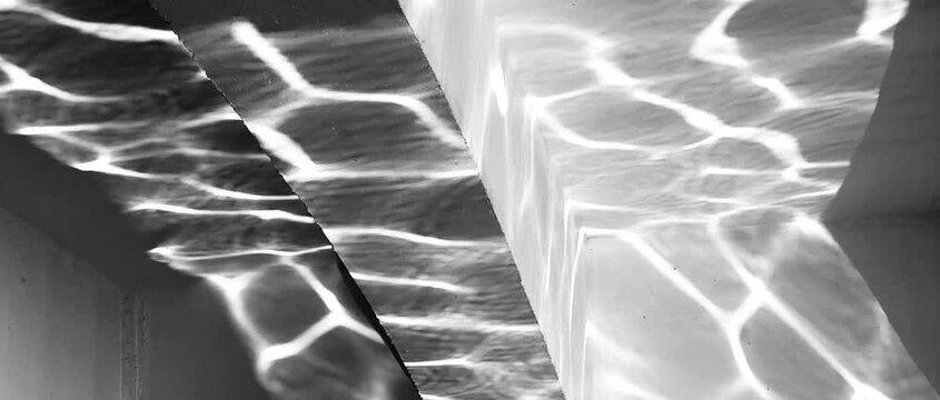 The abstract reflection of rippled water creates dynamic patterns of light on the concrete wall, capturing movement, texture, and the interplay of natural light.