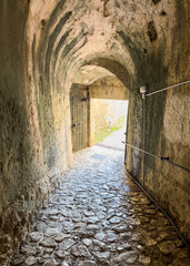 Fototapeta premium Stone tunnel and cobblestone path inside Corfu island New Fortress, Greece. Bright day light at the exit