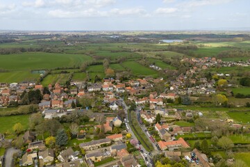 Obraz premium Angled aerial view of Bishop Monkton showing houses gardens roads and surrounding farmland creating a scenic rural village landscape in North Yorkshire during the spring time countryside setting