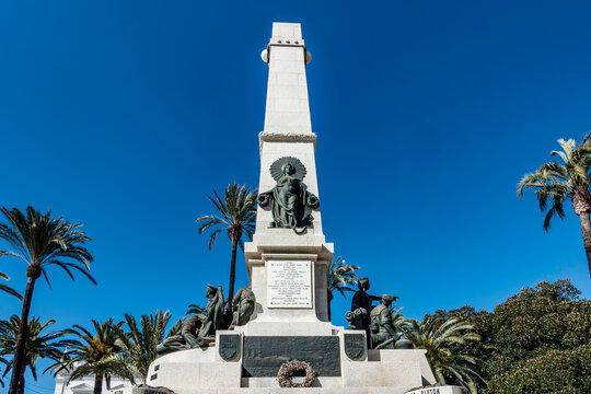 Monumento a los H&eacute;roes de Cavite y Santiago de Cuba in Cartagena, Spain, featuring a stone obelisk with bronze sculptures and palm trees.