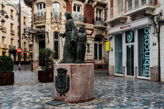 Monumento al Procesionista in Cartagena, Spain, featuring bronze statues of Easter penitents on a marble base in a paved urban plaza.