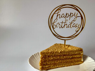 a piece of delicious cake on a white plate on a white background, happy birthday greetings © Polina_mrtnk