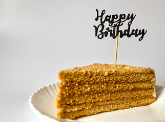 a piece of delicious cake on a white plate on a white background, happy birthday greetings © Polina_mrtnk