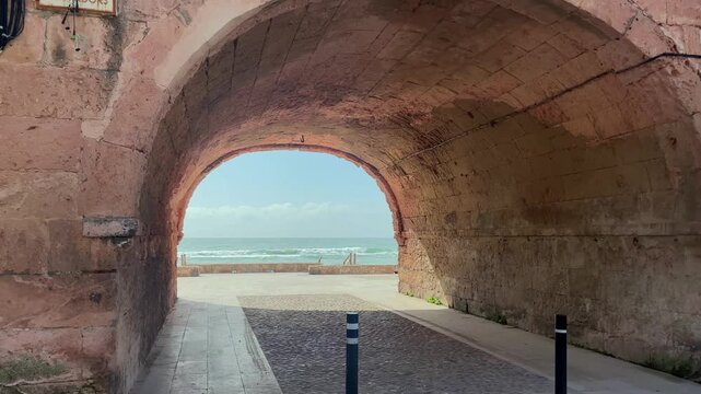 View of the Mediterranean Sea framed through a historic stone arch in Altafulla, Spain