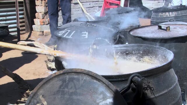 Traditional White Maize Pap Stirred in a traditional black cast iron over an outdoor fire.