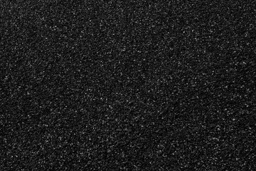 Fototapeta premium black surface fine sea pebbles is textured and uneven. Small stones and gravel are embedded in dark finish. Ideal background or design element.