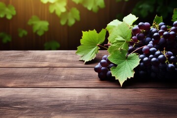 Naklejka premium Dark grapes with green leaves resting on a rustic wooden table under sunlight