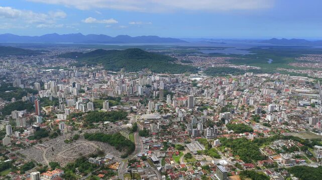 Aerial drone view moving over Joinville city with skyline, hills and coastal landscape.