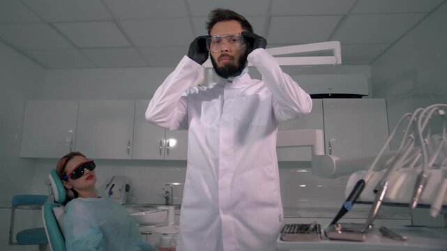 Young handsome dentist prepares for surgery and puts on safety glasses