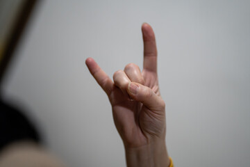 Obraz premium Close-up of a woman’s hand showing “I love you” or rock hand gesture.