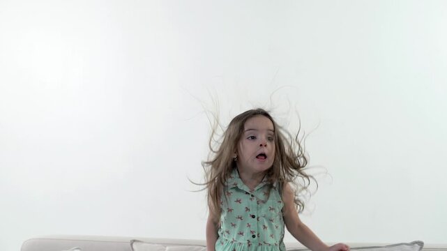 Beautiful cute baby laughing and jumping on the couch against a white background. Slow motion 
