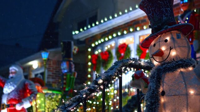 Glowing snowman decoration with Santa statue and house lights. Festive outdoor Christmas display with illuminated snowman and bright holiday lights on house in NYC.