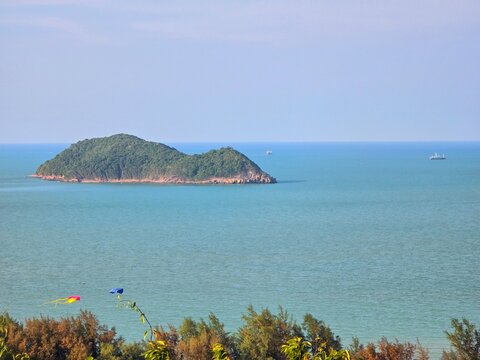 Rat Island tropical landmark surrounded by calm turquoise Gulf of Thailand waters with casuarina trees in foreground, Songkhla, Thailand
