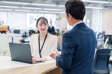Obraz premium 役所の窓口で高齢者に対応する女性スタッフ
