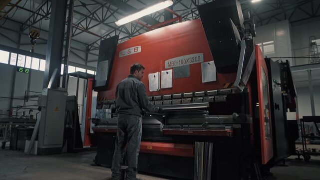 Engineer working behind a state-of-the-art hydraulic sheet metal bending machine press in an automated factory 