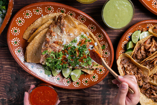 Close-up of a hand adding cilantro to a delicious gringa al pastor on a decorated plate