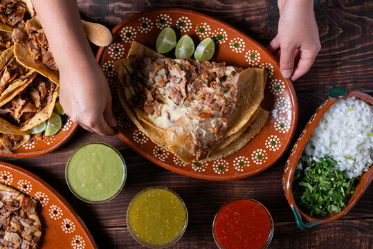 Close-up of a hand adding cilantro to a delicious gringa al pastor on a decorated plate